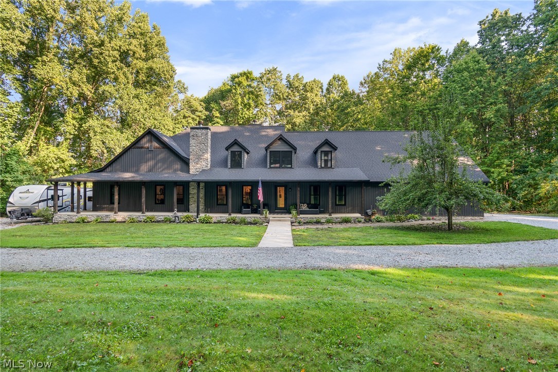 2119 Johns Road Clinton, OH 44216 - Photo 1 of 48 Expansive single-story exterior with dark siding, a covered front porch, stone chimney, and multiple dormer windows