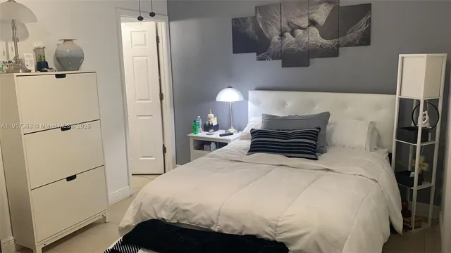 a bedroom with a bed and a lamp on the dresser