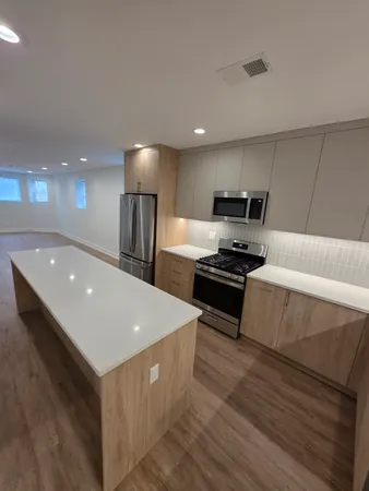 a kitchen with stainless steel appliances a stove a sink a microwave a refrigerator and white cabinets