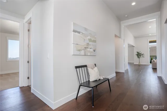 a view of a hallway with wooden floor and a bathroom