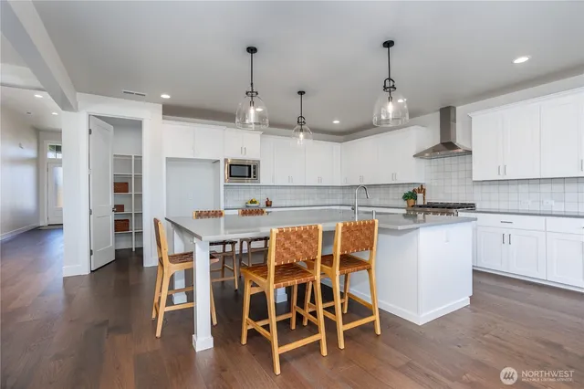 a kitchen with stainless steel appliances kitchen island granite countertop a wooden floor and white cabinets