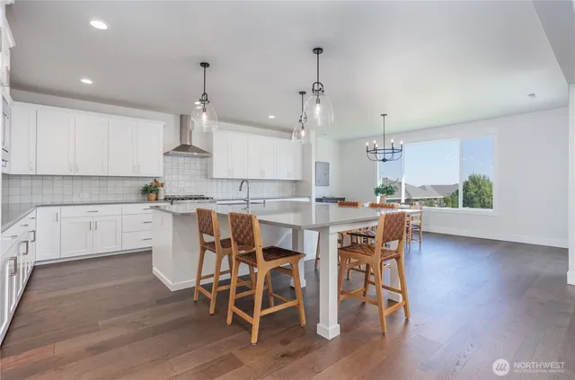 a kitchen with a dining table chairs wooden floor cabinets and stainless steel appliances