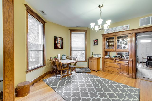 a dining room with chandelier and wooden floor