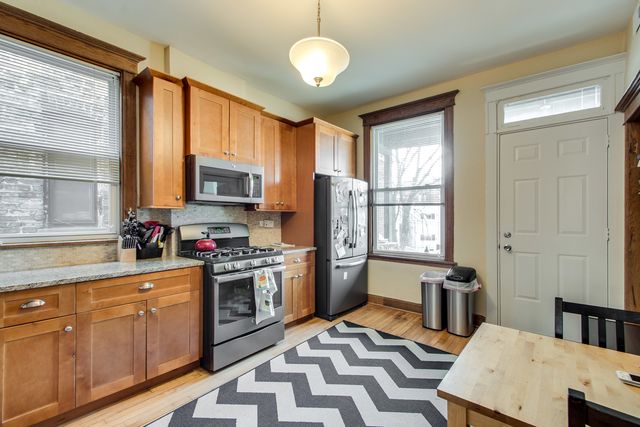 a kitchen with stainless steel appliances granite countertop a stove top oven a sink dishwasher a dining table and chairs with wooden floor