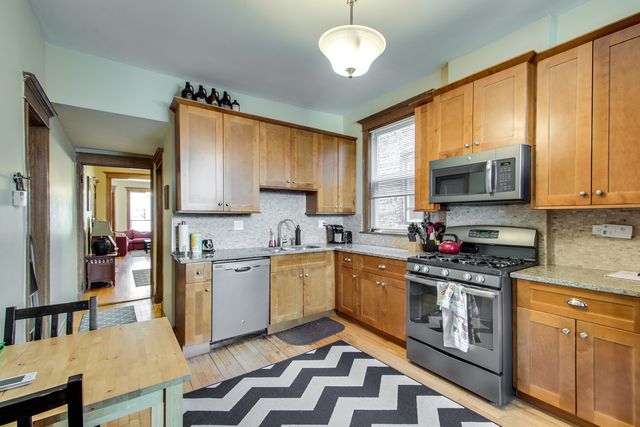 a kitchen with stainless steel appliances granite countertop a stove top oven a sink dishwasher a dining table and chairs with wooden floor