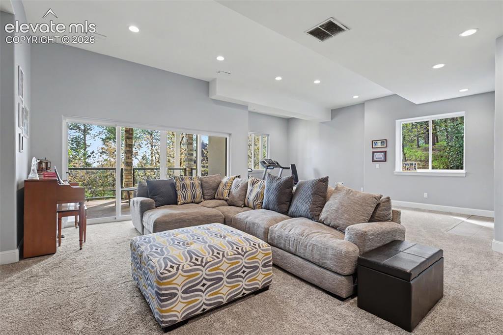 21 Leaming Road Colorado Springs, CO 80906 - Photo 37 of 48 Spacious room featuring multiple large windows and glass sliding doors, recessed lighting, light-colored walls, and neutral carpeting throughout