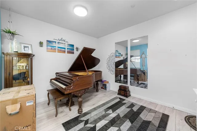 a living room with a piano and wooden floor