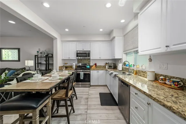 a kitchen with granite countertop kitchen island stainless steel appliances a sink a stove a table and chairs