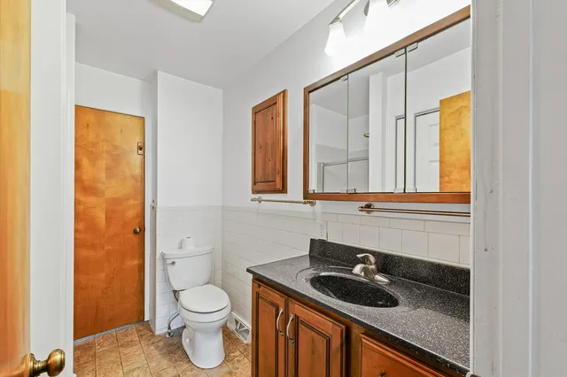 a bathroom with a granite countertop sink toilet and mirror
