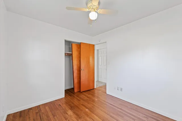 an empty room with wooden floor and fan