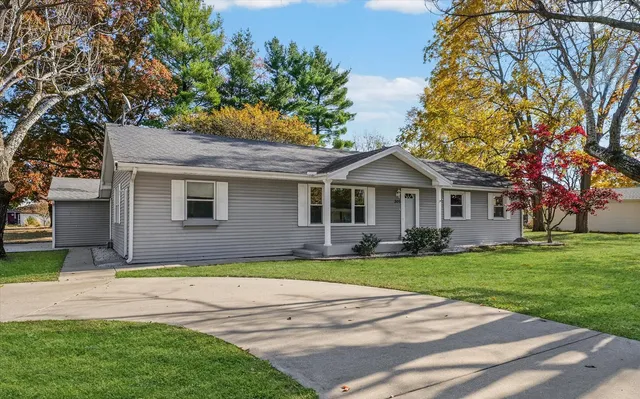 a front view of a house with a garden and trees