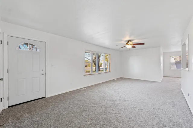 an empty room with windows and chandelier fan