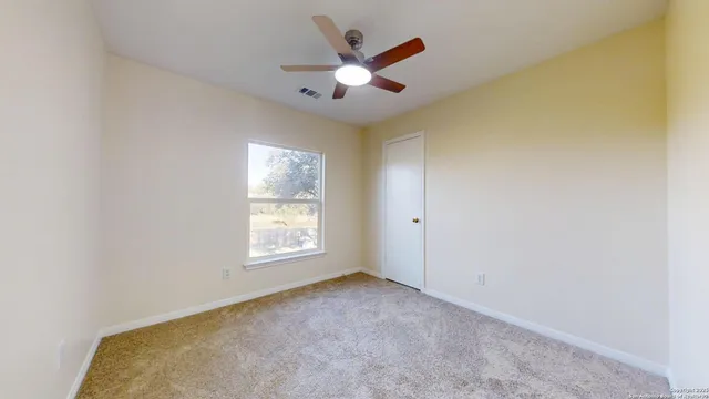 an empty room with ceiling fan and window