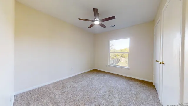 an empty room with a window and a fan