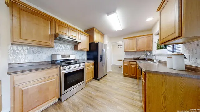 a kitchen with stainless steel appliances granite countertop a stove a sink and a refrigerator