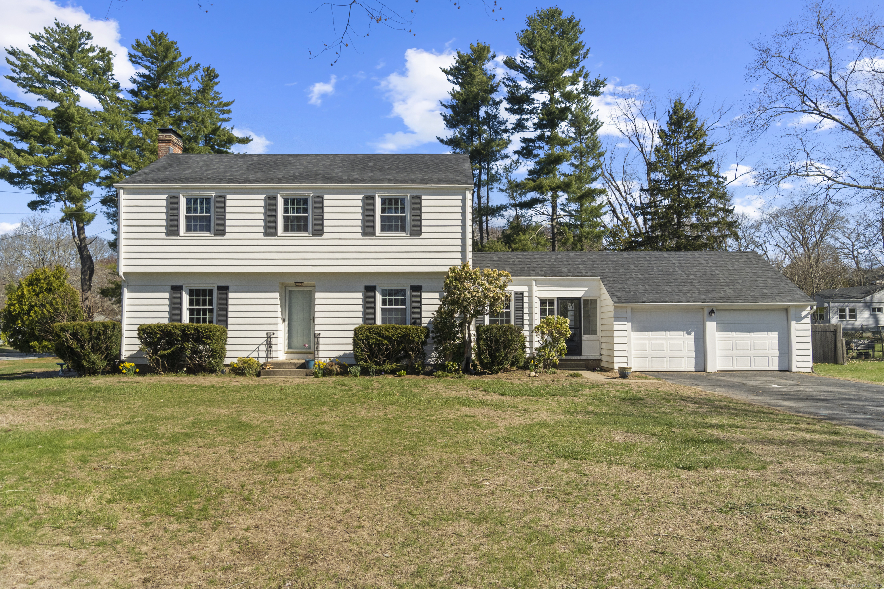 a front view of house with yard and trees in the background