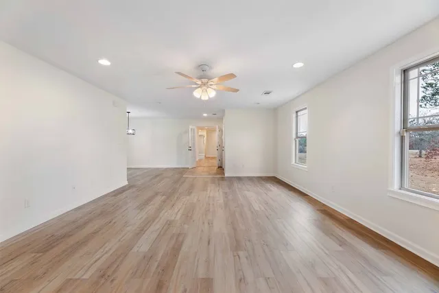 an empty room with wooden floor and windows