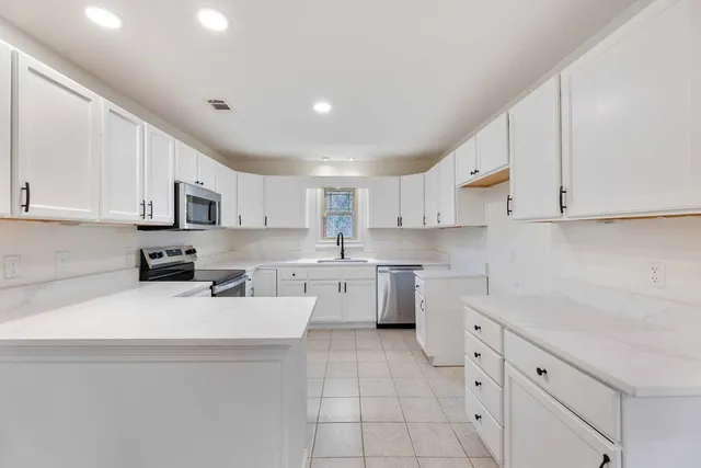 a kitchen with cabinets appliances a sink and a counter top