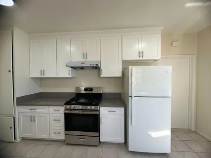 a kitchen with a refrigerator stove and white cabinets