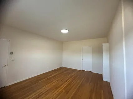 an empty room with wooden floor and natural light