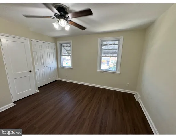 a view of an empty room with wooden floor and window