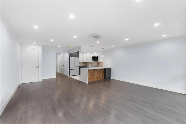 a view of kitchen with kitchen island stainless steel appliances cabinets and wooden floor
