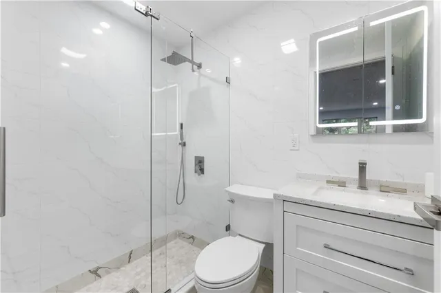a bathroom with a toilet sink vanity and shower
