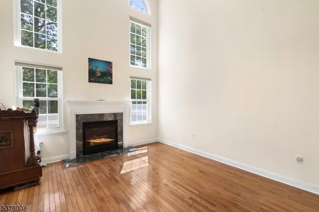 a view of an empty room with wooden floor fireplace and a window