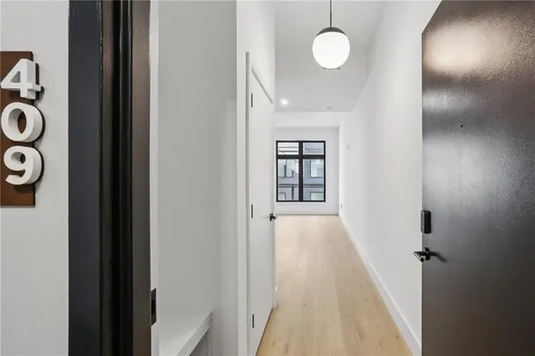 a view of a hallway with wooden floor and cabinets