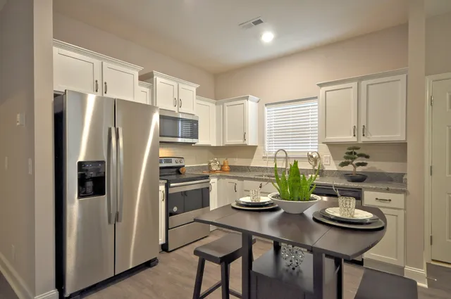 a kitchen with a refrigerator a stove a kitchen island and chairs in it