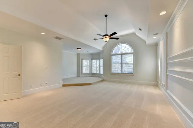 an empty room with ceiling fan and windows