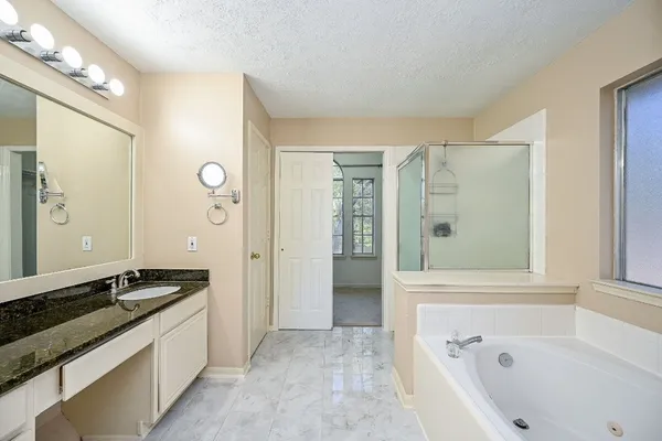 a spacious bathroom with a granite countertop tub sink and mirror