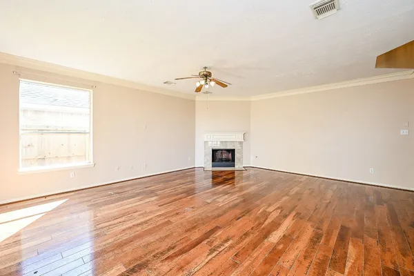 an empty room with wooden floor a ceiling fan and windows