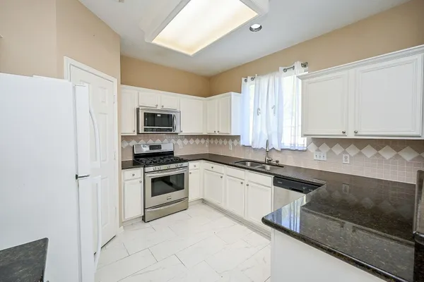 a kitchen with granite countertop white cabinets and stainless steel appliances