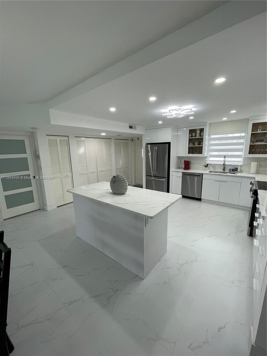 150 South Hollybrook Terrace, Unit 303 Pembroke Pines, FL 33025 - Photo 2 of 18 a large white kitchen with a refrigerator a stove top oven a dining table and chairs