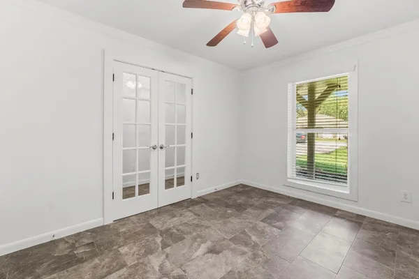 an empty room with windows and fan