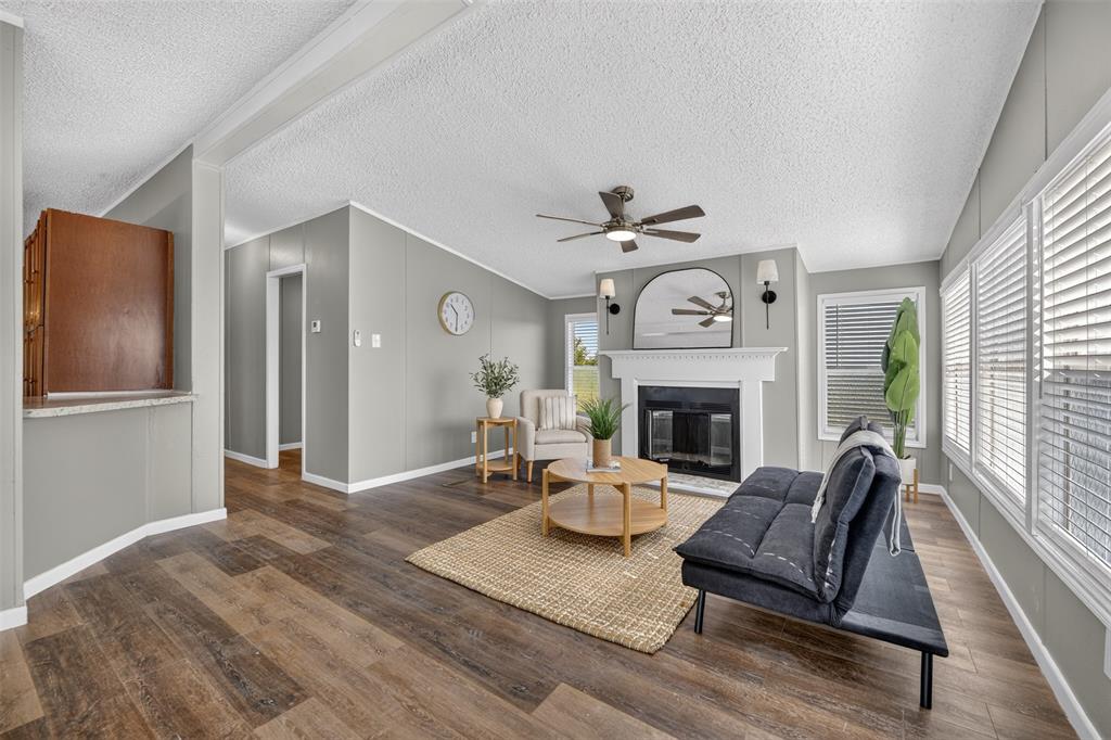449 Big Salty Lane Springtown, TX 76082 - Photo 12 of 25 Spacious living area featuring wood-finish flooring and a white decorative fireplace with sconce lighting