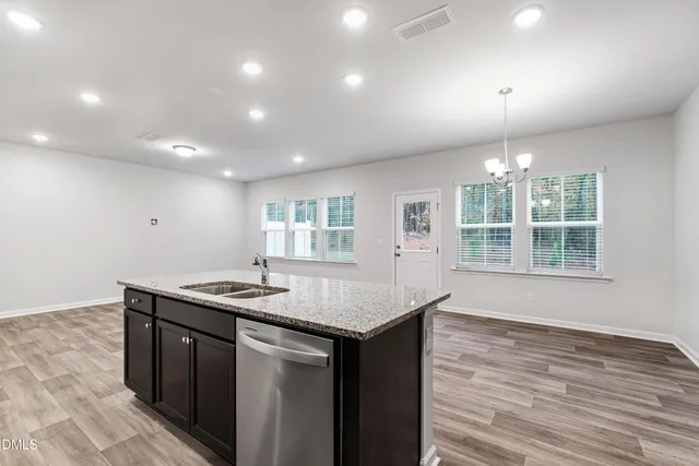 a kitchen with a sink chandelier and wooden floor