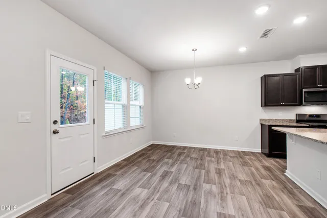 a view of a kitchen from the hallway with a window and wooden floor