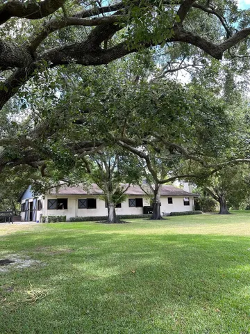 a view of a house with a big yard and large trees