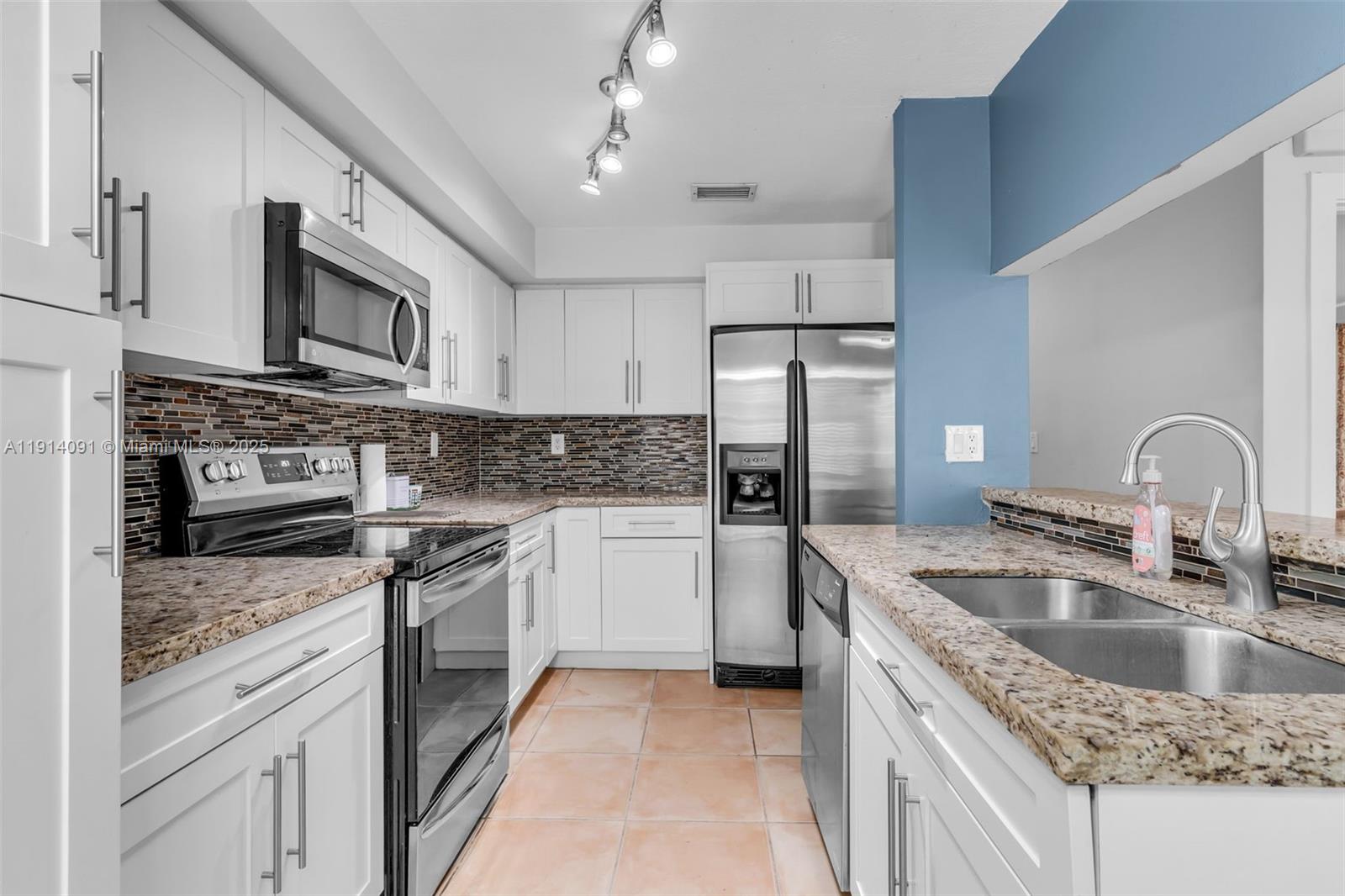 10930 Southwest 75th Street Miami, FL 33173 - Photo 14 of 34 a kitchen with stainless steel appliances granite countertop a sink stove and refrigerator