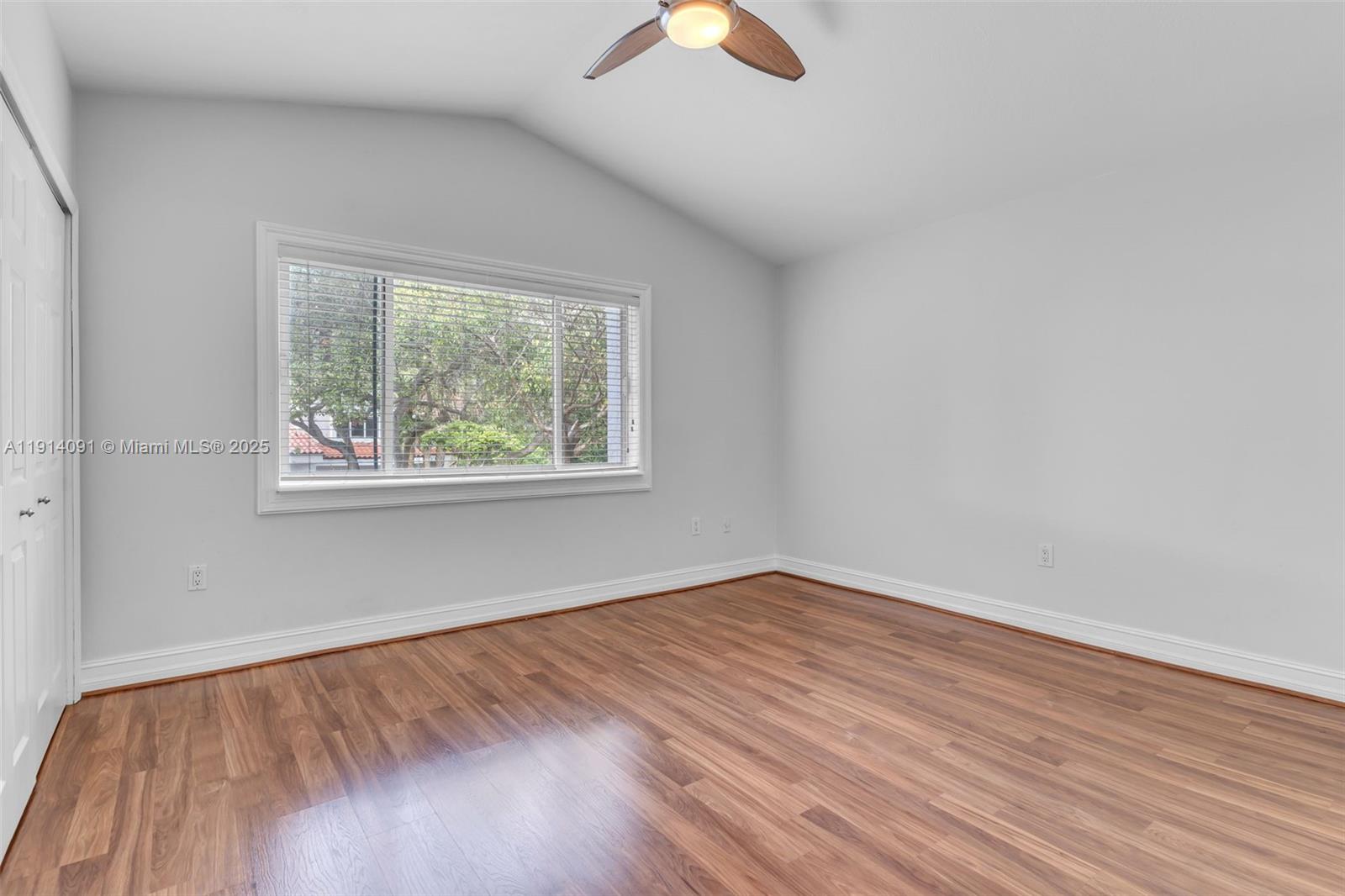 10930 Southwest 75th Street Miami, FL 33173 - Photo 25 of 34 an empty room with wooden floor chandelier fan and windows