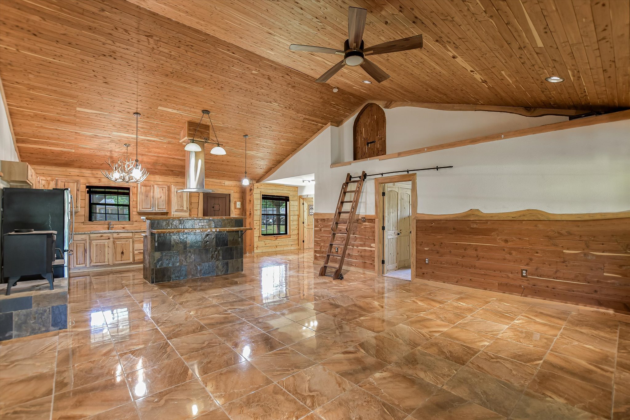 218 Cardinal Loop Paige, TX 78659 - Photo 5 of 22 A spacious, open-concept living area with soaring wood-planked ceilings and sleek tiled flooring.
