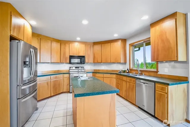 a kitchen with stainless steel appliances granite countertop a refrigerator a sink dishwasher stove and oven