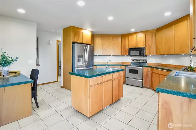 a kitchen with stainless steel appliances granite countertop a stove a sink and a refrigerator