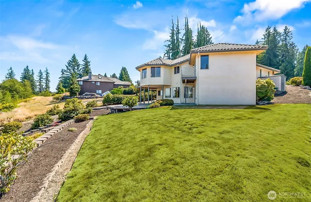 a view of a white house next to a yard with big trees