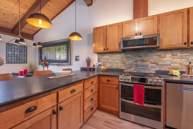 a kitchen with stainless steel appliances granite countertop a stove a sink dishwasher and cabinets with wooden floor