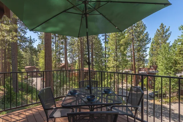 a view of a balcony with chairs and umbrella