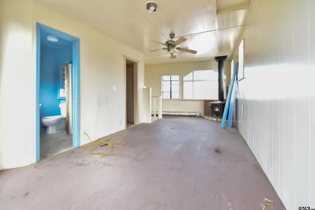 an empty room with chandelier fan and windows