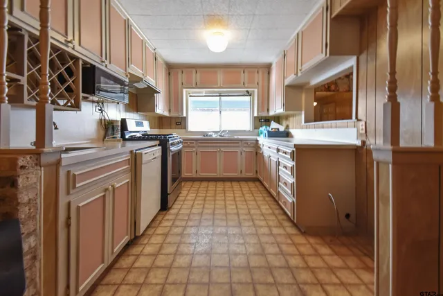 a large kitchen with stainless steel appliances granite countertop a stove top oven a sink dishwasher and cabinets